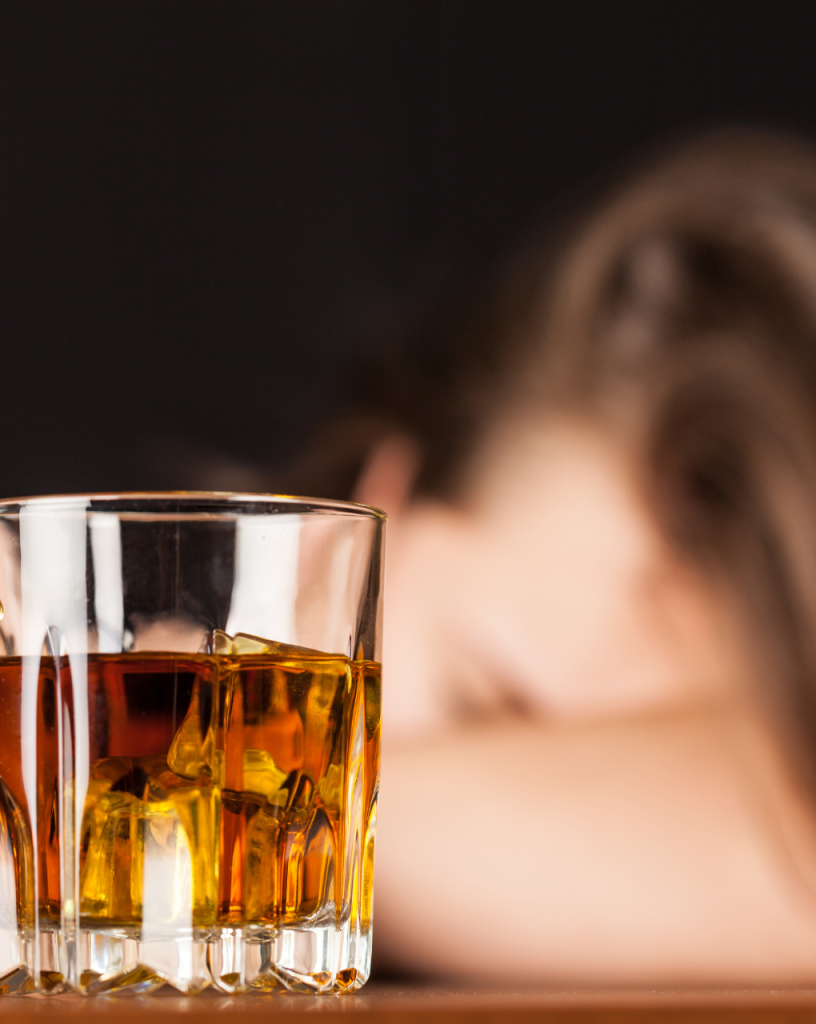 person with their head down with a drink glass in foreground